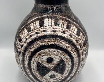 May include: A ceramic vase with a rounded body and a narrow neck. The vase features a textured surface with a pattern of concentric circles and geometric shapes in black, white, and brown. The vase is approximately 10 inches tall.