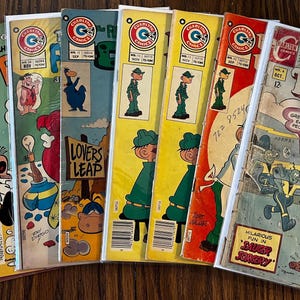 Puede incluir: Una colección de cómics vintage con portadas coloridas. Los cómics presentan varios personajes y títulos, incluyendo "Timmy the Timid Ghost" y "Charlton Comics". Las portadas muestran ilustraciones y texto, con una estética retro.