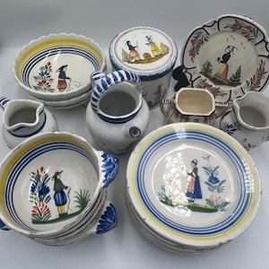 May include: A selection of vintage ceramic tableware with hand-painted designs. The set includes bowls, plates, jugs, and a lidded container. Each piece features a folk art style with figures, floral accents, and blue, yellow, and red colour schemes.