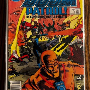 Może przedstawiać: Komiks w stylu vintage zatytułowany "The Doom Patrol!" z dynamiczną ilustracją na okładce. Grafika przedstawia sceny akcji z postaciami w kostiumach w kolorowej, pełnej akcji kompozycji. Widoczne jest logo DC Comics.