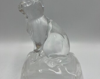 May include: A clear glass cat figurine sitting on a frosted glass base. The cat is in a seated position, with its ears perked up and tail curled. The figurine is a decorative item.