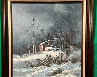 May include: Oil painting of a winter landscape with a snow-covered field and a small red barn. The painting is framed in a dark brown wooden frame with a light beige inner border. Bare trees and a broken wooden fence are in the foreground.