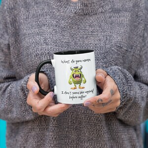 May include: White coffee mug with a black handle and black rim. The mug has a green monster cartoon with the text "What do you mean I don't seem like myself before coffee?"