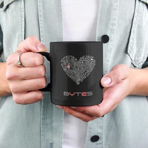 May include: Black ceramic mug with a circuit board design in the shape of a heart. The text "BYTES" is printed in red below the heart.
