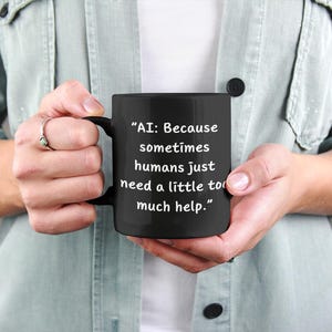 May include: Black coffee mug with white text that reads "AI: Because sometimes humans just need a little too much help."
