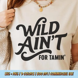 May include: A cream-colored t-shirt with the words "Wild Ain't For Tamin'" in bold, black, cursive font. The shirt also has the text "SVG + PNG | 9 COLORS | 300 DPI | COMMERCIAL USE" at the bottom.