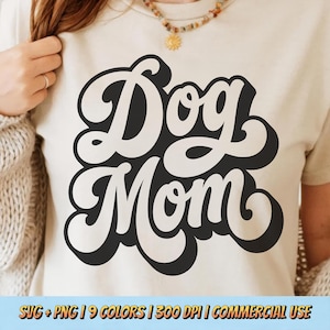 May include: Cream-colored t-shirt with the words "Dog Mom" in a retro, bold, black and white design. The text is in a rounded, playful font. The bottom of the image includes text that reads "SVG + PNG | 9 COLORS | 300 DPI | COMMERCIAL USE".
