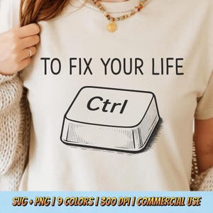 May include: Beige t-shirt with the text "TO FIX YOUR LIFE" above a graphic of a Ctrl key. The Ctrl key is in black and white. The shirt is a neutral color and has a simple design.