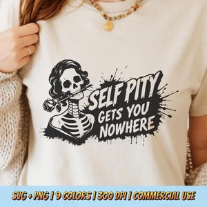 May include: Cream-coloured t-shirt with a black and white skeleton graphic holding a rose, and the words "SELF PITY GETS YOU NOWHERE". The design includes a splatter effect.
