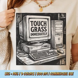 May include: Beige t-shirt featuring a black and white graphic of an old computer setup. The computer screen displays the text "TOUCH GRASS IMMEDIATELY". The design includes a monitor, tower, keyboard, and mouse.