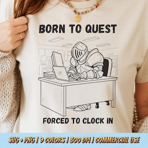 May include: Beige t-shirt with a black and white illustration of a knight in armor working on a laptop at a desk. The text "BORN TO QUEST" is above the illustration, and "FORCED TO CLOCK IN" is below.