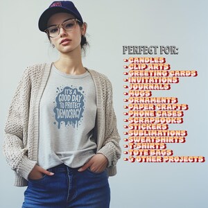 May include: A light gray t-shirt with the text "IT'S A GOOD DAY TO PROTECT DEMOCRACY" in blue. The image also shows a woman wearing a navy blue baseball cap, glasses, and a beige cardigan. The text "PERFECT FOR" is also visible.