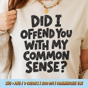 以下が含まれることがあります： 「DID I OFFEND YOU WITH MY COMMON SENSE？」と黒い太字で書かれたベージュ色のTシャツ。画像には、Tシャツを着ている人が写っており、ネックレスも見えます。下部には「SVG + PNG | 9 COLORS | 300 DPI | COMMERCIAL USE」と書かれています。