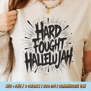 May include: Cream-colored t-shirt with the words "HARD FOUGHT HALLELUJAH" in bold, black, brush-style lettering. The text is surrounded by radiating lines and dots. The bottom of the image has text that reads "SVG + PNG | 9 COLORS | 300 DPI | COMMERCIAL USE".