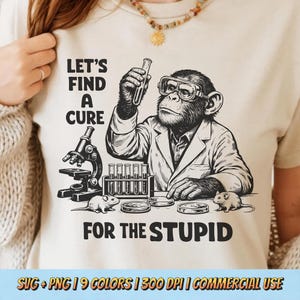 May include: Beige t-shirt with a black and white graphic of a chimpanzee in a lab coat, holding a test tube. The text reads "LET'S FIND A CURE FOR THE STUPID". Includes a microscope, test tubes, petri dishes, and mice.