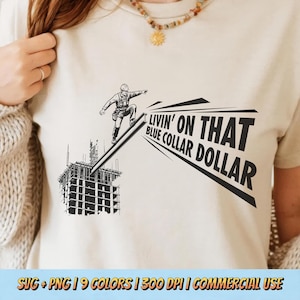 May include: Beige t-shirt featuring a black and white graphic of a construction worker sliding down a beam, with the text "LIVIN' ON THAT BLUE COLLAR DOLLAR". The shirt also includes the text "SVG + PNG | 9 COLORS | 300 DPI | COMMERCIAL USE".