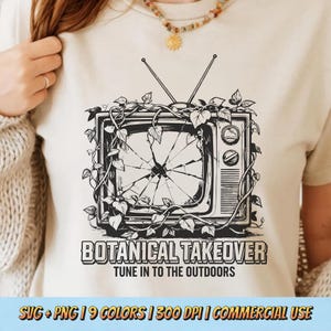 May include: Beige t-shirt featuring a black and white graphic of a vintage television with a shattered screen, vines, and leaves. The text reads "BOTANICAL TAKEOVER" and "TUNE IN TO THE OUTDOORS".