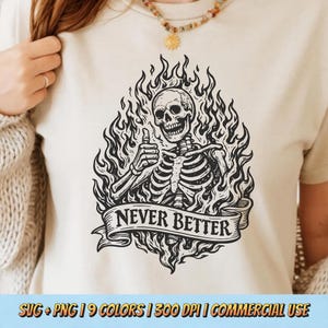 May include: Beige t-shirt featuring a black and white illustration of a skeleton giving a thumbs up, surrounded by flames. A banner below reads "NEVER BETTER". The shirt also includes text at the bottom.