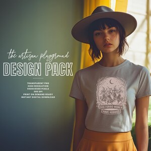 May include: A woman wearing a gray t-shirt with a graphic design and text. The design features a crescent moon, figures, and the words "GOD FORBID WOMEN HAVE HOBBIES." The image also includes text that says "the artisan playground DESIGN PACK."