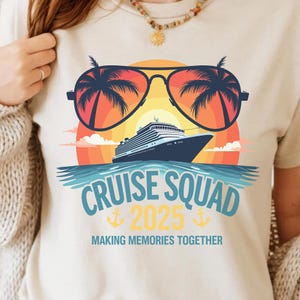 Peut inclure: Un t-shirt blanc avec un motif graphique représentant un navire de croisière naviguant dans un coucher de soleil avec des palmiers reflétés dans des lunettes de soleil. Le texte "Cruise Squad 2025" est sous le navire avec des ancres de chaque côté. Le texte "Making Memories Together" est sous les ancres.