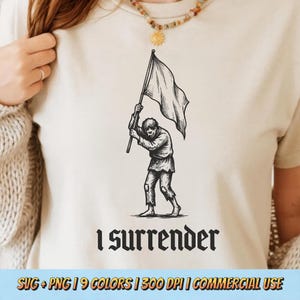 May include: Cream-colored t-shirt featuring a black and white illustration of a person holding a white flag, with the words "I surrender" in a gothic font below. The design is a vintage-style graphic.