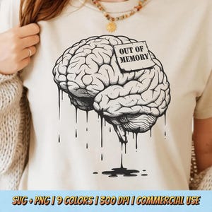 以下が含まれることがあります： ベージュ色のTシャツ。脳の白黒イラストと「OUT OF MEMORY」の文字が付いた付箋が描かれています。脳のデザインには、インクが滴り落ちるような効果があります。