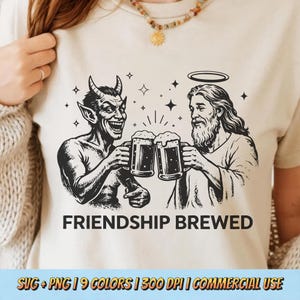 Puede incluir: Camiseta beige con un gráfico en blanco y negro de un diablo y Jesús brindando con jarras de cerveza. El texto "FRIENDSHIP BREWED" está debajo de la ilustración. La camiseta también tiene el texto "SVG + PNG | 9 COLORS | 300 DPI | COMMERCIAL USE".