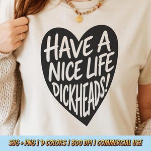 Puede incluir: Camiseta color crema con un corazón negro con el texto blanco "HAVE A NICE LIFE DICKHEADS!". La camiseta tiene mangas cortas y la lleva una persona. La parte inferior de la imagen incluye texto: SVG + PNG | 9 COLORS | 300 DPI | USO COMERCIAL.