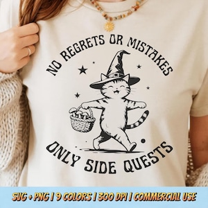 May include: Cream-colored t-shirt featuring a cartoon cat wearing a witch hat and carrying a basket of mushrooms. The text reads "NO REGRETS OR MISTAKES ONLY SIDE QUESTS". The design includes stars and is suitable for commercial use.
