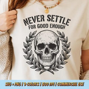 Può includere: T-shirt color crema con un design dettagliato di teschio in bianco e nero, circondato da una corona d'alloro. Il testo "NEVER SETTLE FOR GOOD ENOUGH" è stampato sopra il teschio. La parte inferiore della maglietta riporta la scritta "SVG + PNG | 9 COLORS | 300 DPI | COMMERCIAL USE."