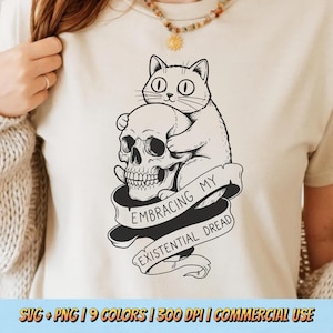 May include: Cream-colored t-shirt featuring a black and white graphic of a cat hugging a skull. A banner below reads "Embracing My Existential Dread." The bottom of the image includes text about colors, DPI, and commercial use.