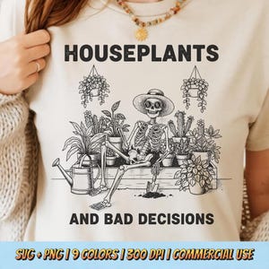 May include: Beige t-shirt with a black and white graphic featuring a skeleton wearing a hat and sunglasses, surrounded by potted plants. The text reads "HOUSEPLANTS AND BAD DECISIONS".