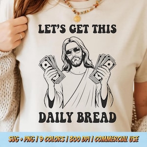 May include: Beige t-shirt with a black graphic of a Jesus-like figure wearing sunglasses and holding stacks of money. The text "LET'S GET THIS DAILY BREAD" is above and below the image. The bottom of the shirt has text that reads "SVG + PNG | 9 COLORS | 300 DPI | COMMERCIAL USE".