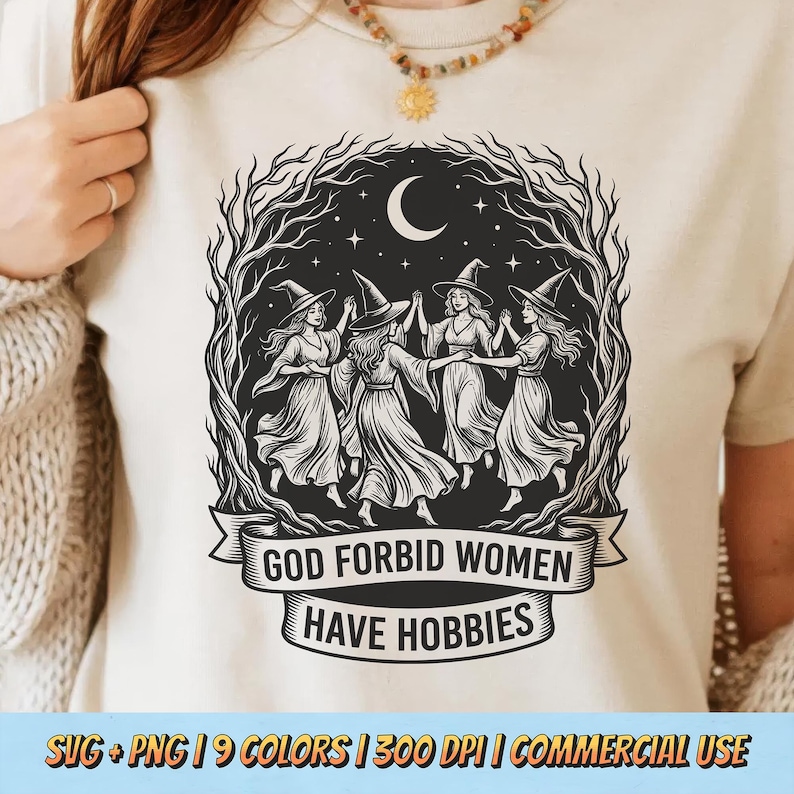 May include: Beige t-shirt featuring a black and white illustration of four women in witch hats dancing in a circle under a crescent moon. The text "GOD FORBID WOMEN HAVE HOBBIES" is displayed on a banner below the image.