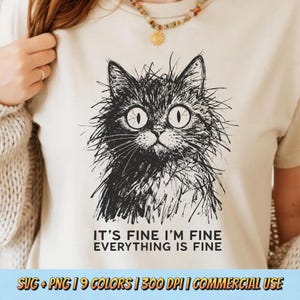 May include: A cream-colored t-shirt featuring a black and white illustration of a cat with wide eyes. The text "IT'S FINE I'M FINE EVERYTHING IS FINE" is printed below the cat. The shirt is a casual wear item.