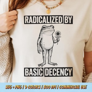 May include: Beige t-shirt with the text "RADICALIZED BY BASIC DECENCY" in black. A black and white illustration of a frog holding a sunflower is centered on the shirt. The shirt also has the text "SVG + PNG | 9 COLORS | 300 DPI | COMMERCIAL USE".
