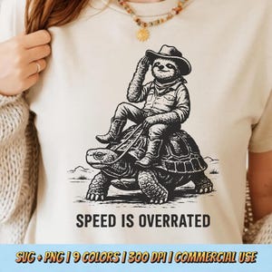 May include: A beige t-shirt featuring a black and white illustration of a sloth wearing a cowboy hat and riding a tortoise. The text "SPEED IS OVERRATED" is below the image. The bottom of the image has text that reads "SVG + PNG | 9 COLORS | 300 DPI | COMMERCIAL USE".