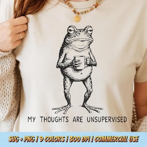 Puede incluir: Camiseta beige con una ilustración en blanco y negro de una rana sosteniendo una taza. El texto "MY THOUGHTS ARE UNSUPERVISED" está impreso debajo. La parte inferior de la imagen incluye información sobre el formato y el uso comercial del diseño.