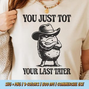 May include: A cream-colored t-shirt with the text "YOU JUST TOT YOUR LAST TATER." The shirt features a black and white illustration of an angry potato wearing a cowboy hat. The design is a humorous take on a classic phrase.