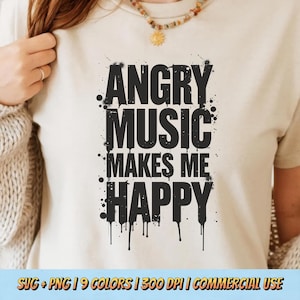 May include: A cream-colored t-shirt with the text "ANGRY MUSIC MAKES ME HAPPY" in bold, black letters. The text has a distressed, spray-paint style with black drips and splatters. The shirt is a casual wear item.