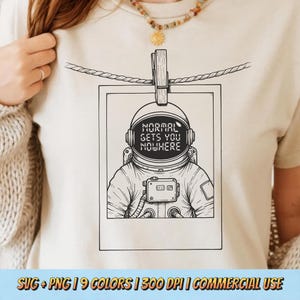 Może przedstawiać: Kremowy t-shirt z czarno-białą ilustracją astronauty w ramce polaroid. Hełm astronauty wyświetla napis "NORMAL GETS YOU NOWHERE". Polaroid jest przypięty do sznurka drewnianym spinaczem do bielizny.