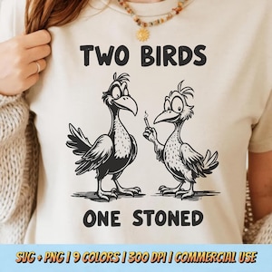 May include: A beige t-shirt with a black and white cartoon of two birds. One bird holds a lit cigarette. The text "TWO BIRDS ONE STONED" is printed above and below the birds in a bold font.