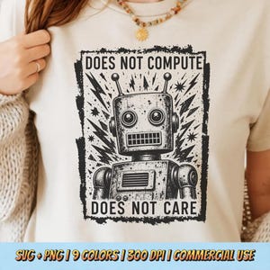 May include: A cream-colored t-shirt featuring a black graphic of a retro robot with antennas, surrounded by jagged lightning bolt shapes. The text "DOES NOT COMPUTE" is printed above the robot, and "DOES NOT CARE" is printed below the robot.