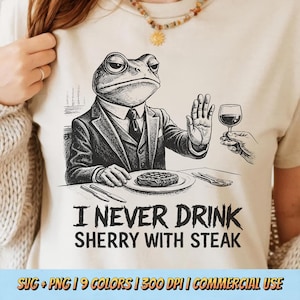 Könnte beinhalten: Beigefarbenes T-Shirt mit einer Schwarz-Weiß-Illustration eines Frosches im Anzug, der ein Weinglas ablehnt. Der Text "I NEVER DRINK SHERRY WITH STEAK" steht darunter. Das T-Shirt hat einen Rundhalsausschnitt.
