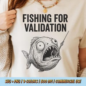 May include: Beige t-shirt with the text "FISHING FOR VALIDATION" above a detailed black and white illustration of a fish caught on a hook. The fish has wide eyes and an open mouth. The bottom of the image has text that reads "SVG + PNG | 9 COLORS | 300 DPI | COMMERCIAL USE".