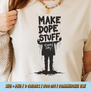 Op de afbeelding: Crèmekleurig T-shirt met een zwarte afbeelding van een persoon die een bord vasthoudt met de tekst "MAKE DOPE STUFF EVERY DAY". Het ontwerp heeft een druipend verfeffect. Het shirt maakt deel uit van een collectie met 9 kleuren en is voor commercieel gebruik.