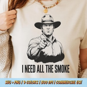 May include: A beige t-shirt featuring a black and white illustration of a man in a cowboy hat pointing at the viewer. The text "I NEED ALL THE SMOKE" is below the image. The bottom of the shirt has text that reads "SVG + PNG | 9 COLORS | 300 DPI | COMMERCIAL USE."