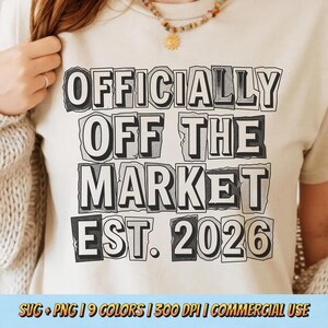 May include: A cream-colored t-shirt with the text "OFFICIALLY OFF THE MARKET EST. 2026" in a black, newspaper-style font. The shirt is a casual style, suitable for everyday wear. The image also includes text at the bottom.