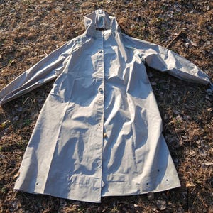 Może przedstawiać: Zestaw trzech ceramicznych kubków z nakrapianym, matowym wykończeniem. Kubki są w odcieniach kremu, jasnoszarym i ciemnoszarym. Każdy kubek ma prosty, minimalistyczny design i zaokrąglony uchwyt.