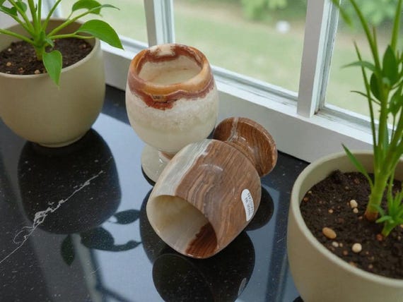 Tiny hand-carved green onyx goblets that are simultaneously functional mini drinkware and sculptural stone objects — genuinely unusual and conversation-starting.